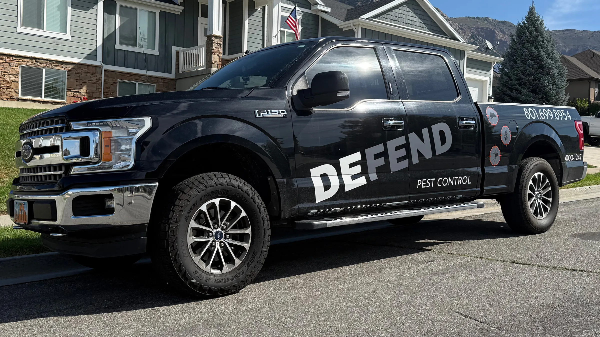 Ken's Defend Pest Control truck parked at a home below the Wasatch Mountains